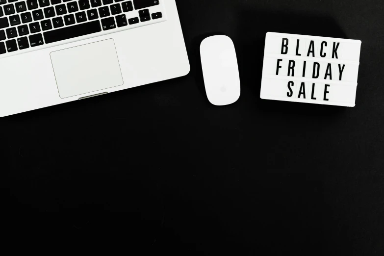 a laptop computer sitting on top of a desk next to a mouse, a black and white photo, by Julia Pishtar, trending on unsplash, magazine sales, black skin!!!, flatlay, holiday