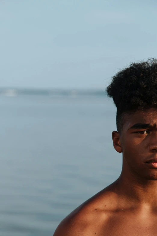 a man standing in front of a body of water, an album cover, by Carey Morris, unsplash, black teenage boy, headshot, 15081959 21121991 01012000 4k, hair