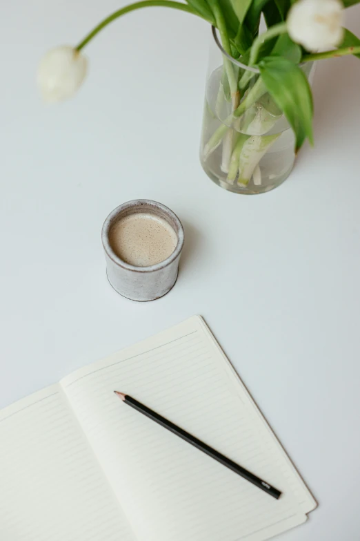 a cup of coffee and a notebook on a table, unsplash, minimalism, silver，ivory, glass jar, environmental shot, dwell