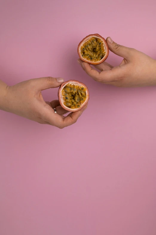 two hands holding two halves of a passion fruit, by Matthias Stom, trending on unsplash, magic realism, pink and orange, made of glazed, photoshoot for skincare brand, adult pair of twins