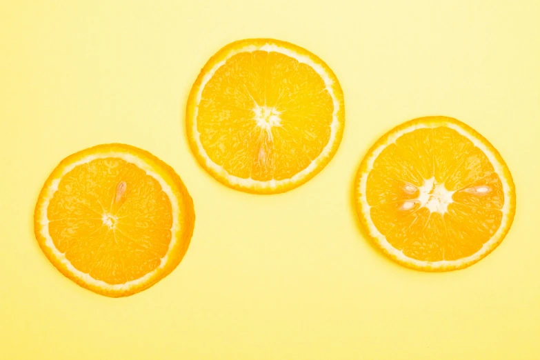 three oranges cut in half on a yellow background, trending on pexels, minimalism, 🦩🪐🐞👩🏻🦳, orange mist, shot on canon eos r5, the three suns