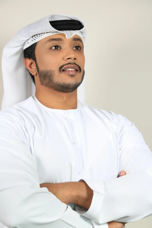 a man standing with his arms crossed, an album cover, inspired by Sheikh Hamdullah, pexels contest winner, wearing white cloths, basic background, dubai, ((portrait))