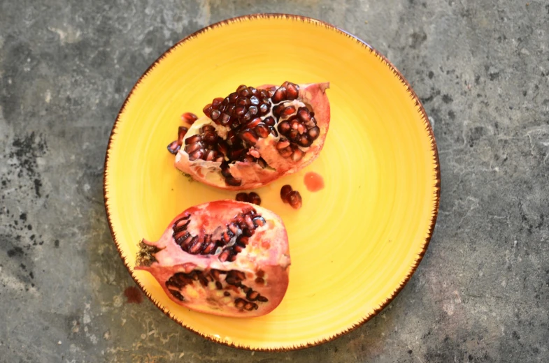 two pomegranates sitting on a yellow plate, by Carey Morris, pexels, square, recipe, stuffed, jen yoon