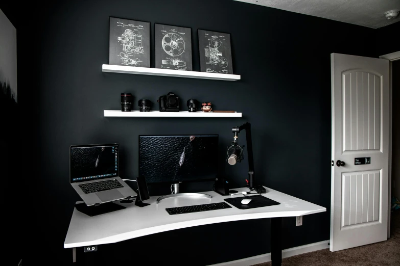 a laptop computer sitting on top of a white desk, a black and white photo, by Ben Zoeller, computer art, apartment with black walls, shelves, gaming room, taken with sony alpha 9