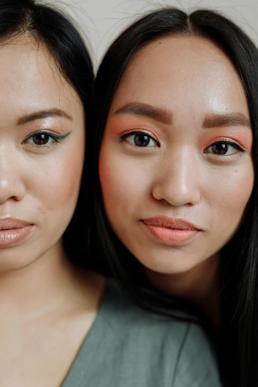 a couple of women standing next to each other, inspired by Wang Duo, trending on pexels, complimentary eyeliner, malaysian, iridescent skin, orange hue