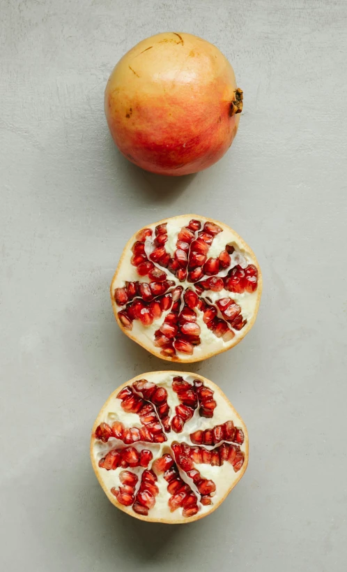 three pomegranates cut in half on a table, by Carey Morris, pexels, on a gray background, top down view, jen yoon, hegre