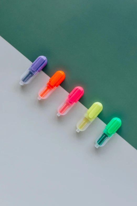 a group of pens sitting on top of a table, translucent neon skin, detailed product image, top down shot, 5 7 9