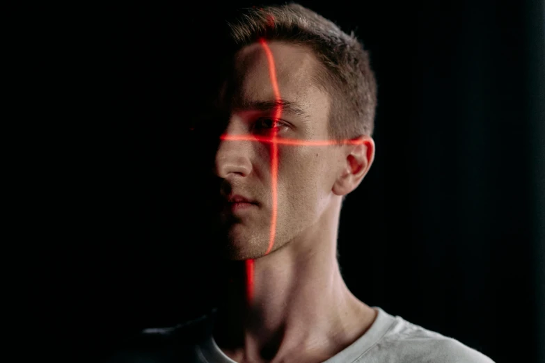 a man with a red cross on his face, pexels contest winner, holography, linus from linustechtips, headshot profile picture, red laser scanner, split near the left