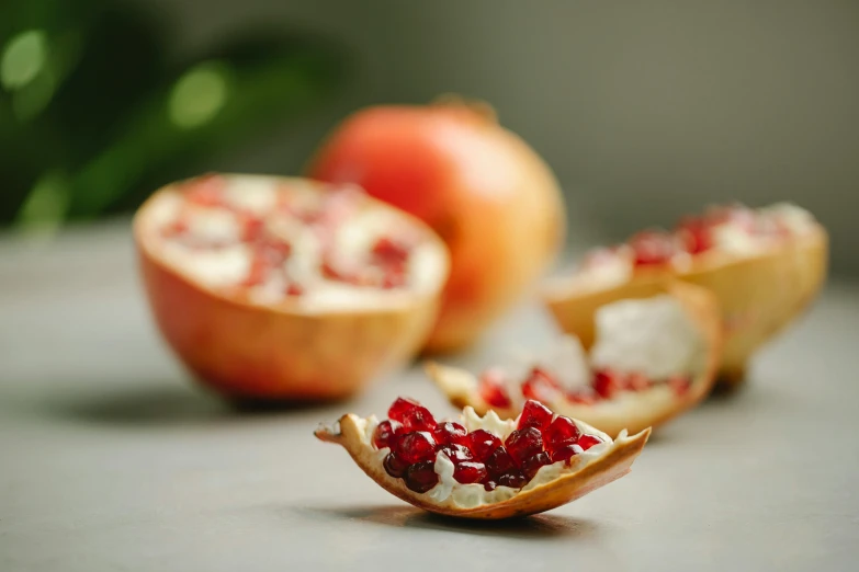 a pomegranate cut in half on a table, pexels, arabesque, crisps, payne's grey and venetian red, mid shot, on grey background