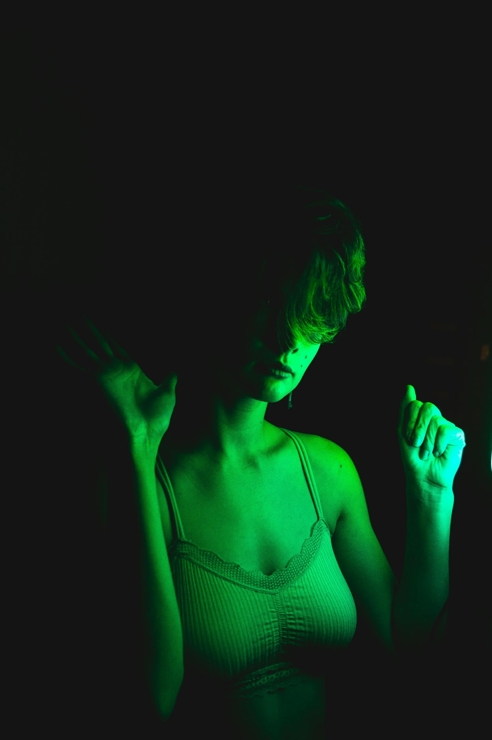 a woman holding a cell phone in the dark, an album cover, inspired by Elsa Bleda, pexels, visual art, green body, model posing, green concert light, pale woman