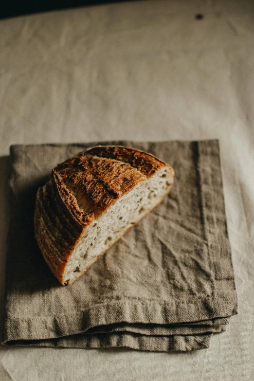 a loaf of bread sitting on top of a napkin, a portrait, unsplash, arched back, fertile, gray canvas, hip-length