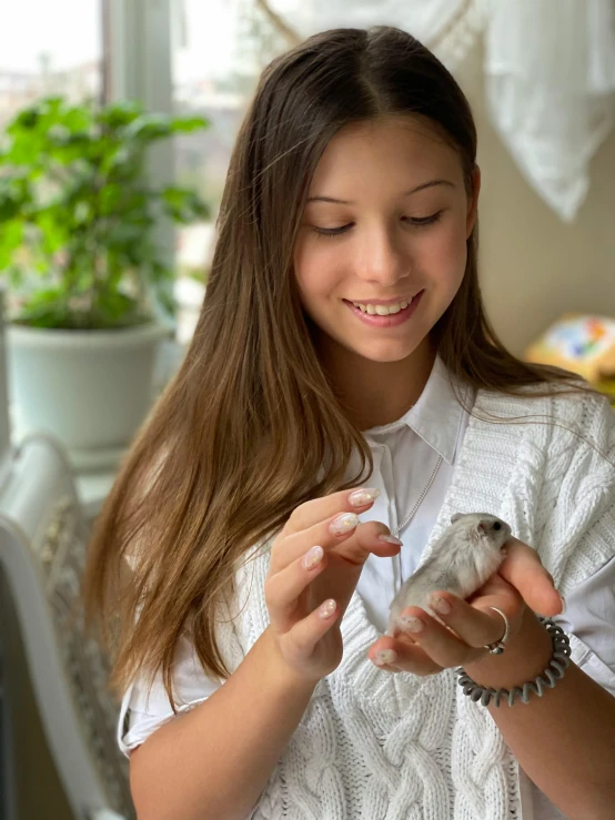 a woman holding a small bird in her hands, isabela moner, hamsters, profile image, at home