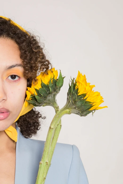 a woman holding a sunflower in front of her face, an album cover, inspired by Jean-Étienne Liotard, trending on pexels, mixed race, kiko mizuhara, loosely cropped, mid length portrait photograph