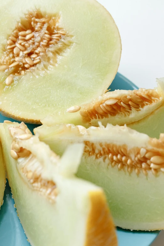 a cantaloupe cut in half on a blue plate, hurufiyya, close up of iwakura lain, pale green backlit glow, seeds, promo image