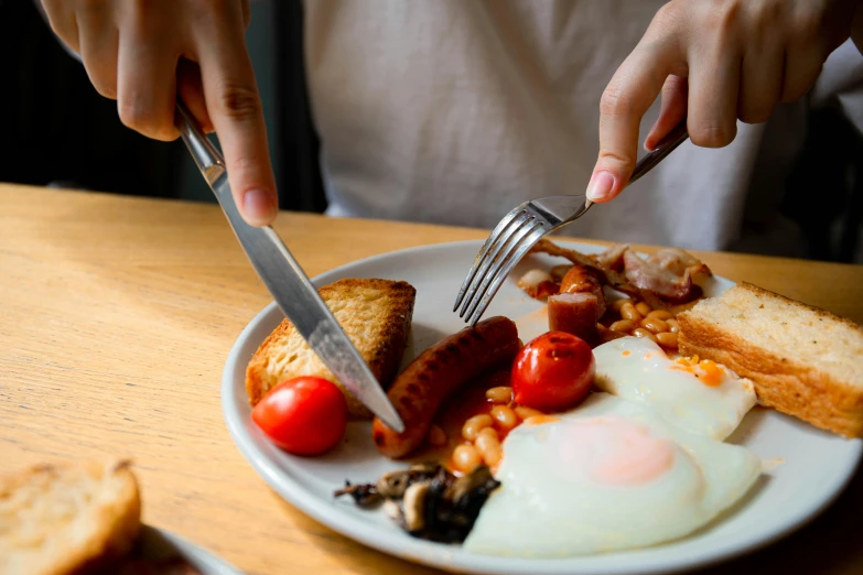 a person sitting at a table with a plate of food, pexels contest winner, hearty breakfast, holding a knife, 🦩🪐🐞👩🏻🦳, eggs