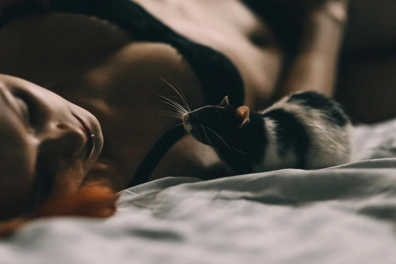 a woman laying on top of a bed next to a rat, by Emma Andijewska, pexels contest winner, cat ears and cat tail!, sexy movie photo, they are close to each other, sugar glider