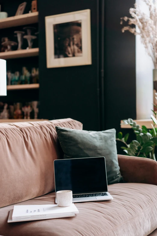 a laptop computer sitting on top of a brown couch, trending on pexels, black and terracotta, pink accents, distant photo, lounge