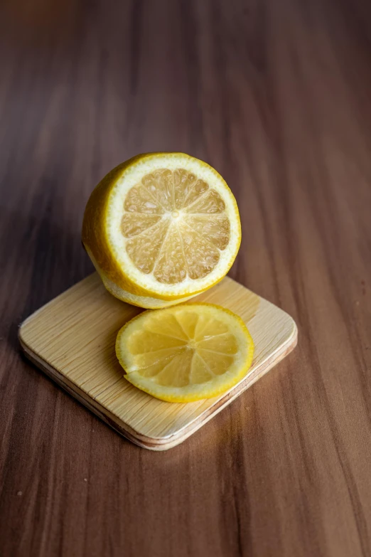 a sliced lemon sitting on top of a wooden cutting board, square, detailed product image, medium angle, widest shot