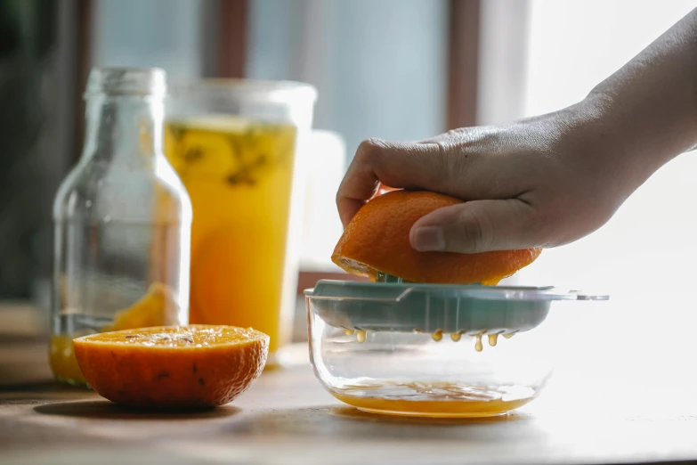 a person squeezing an orange into a bowl, inside a glass jar, 🦩🪐🐞👩🏻🦳, mixing drinks, uncropped