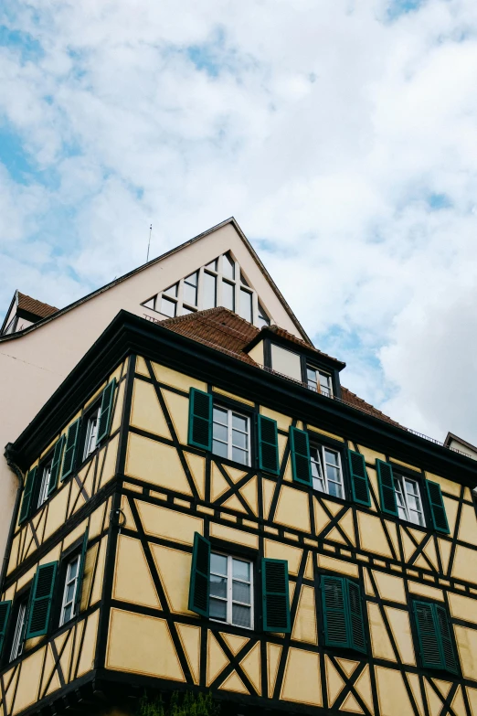 a tall building with a clock on top of it, a photo, by Tobias Stimmer, trending on unsplash, renaissance, timbered house with bricks, yellow and greens, frank gehry, square