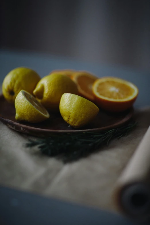 a plate of lemons sitting on top of a table, a still life, pexels, grey orange, subtle details, greens), moody details