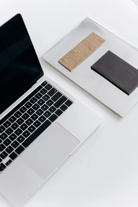 a laptop computer sitting on top of a white desk, by Carey Morris, trending on unsplash, sustainable materials, black on white background, pair of keycards on table, brown and white color scheme