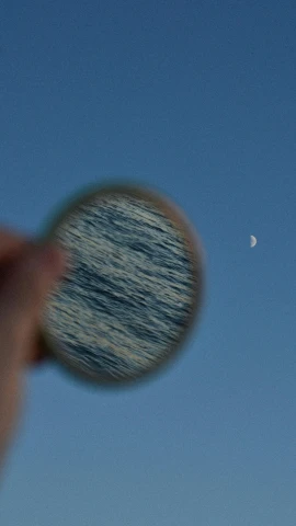 a person looking at the moon through a magnifying lens, inspired by Vija Celmins, unsplash, purism, still water calm as a mirror, polarizer filter : 1 0, birdseye view, seaview