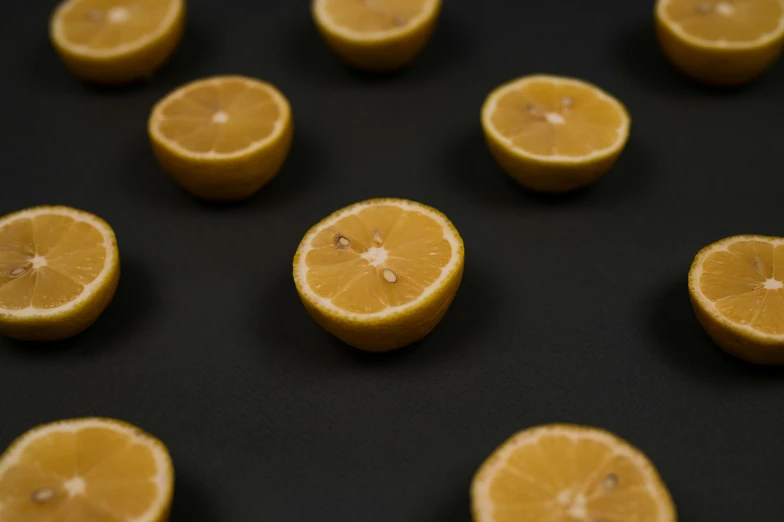 a bunch of oranges sitting on top of a table, in front of a black background, a round minimalist behind, wearing a lemon, subtle detailing