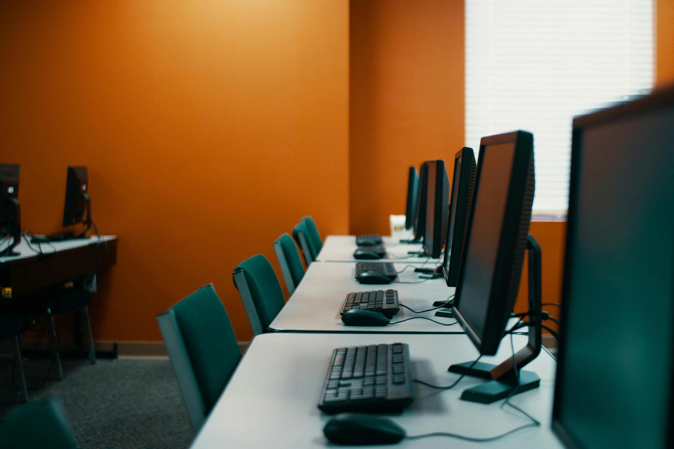 a row of computers sitting on top of a white table, profile image, studio orange, background image, in a classroom