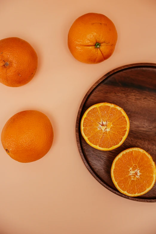 a wooden plate topped with oranges on top of a table, by Carey Morris, trending on unsplash, orange backgorund, detailed product image, full body image, detailed product photo