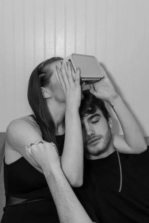 a man covering his eyes while sitting next to a woman, a black and white photo, by Alexis Grimou, vr headset, couple kissing, vhs style, boy and girl