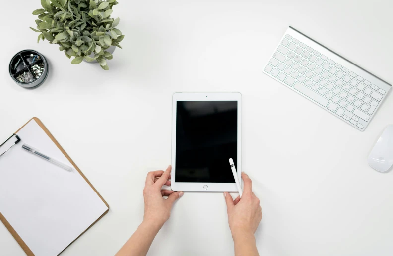 a person using a tablet computer on a desk, by Carey Morris, trending on unsplash, clean white background, background image, high angle shot, professional product shot