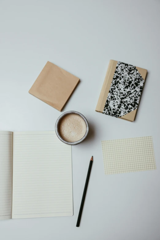 an open notebook sitting on top of a table next to a cup of coffee, trending on unsplash, visual art, black squares on 4 corners, natural materials, delicate patterned, thumbnail