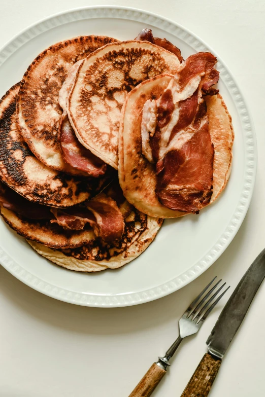 a white plate topped with pancakes covered in bacon, a portrait, unsplash, high quality picture, orthodox, faded worn, thumbnail