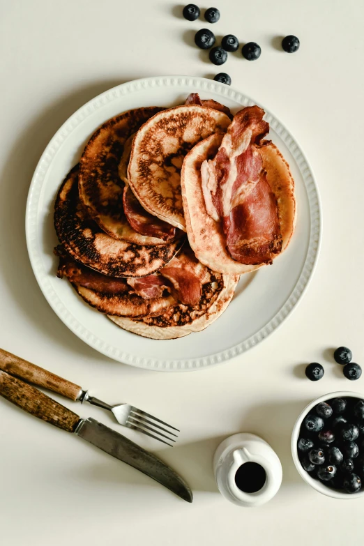 a white plate topped with pancakes and blueberries, a portrait, unsplash, bacon, studio shot, sunfaded, 0