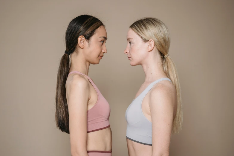 a couple of women standing next to each other, inspired by Vanessa Beecroft, trending on pexels, renaissance, sport bra, faces look at each other, mixed race, high resolution