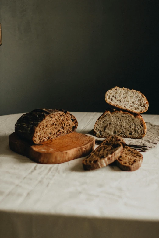 a loaf of bread sitting on top of a wooden cutting board, a portrait, unsplash, renaissance, brown bread with sliced salo, thumbnail, various posed, indoor shot