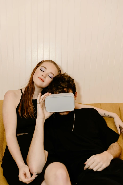 a man and a woman sitting on a couch, an album cover, by Carey Morris, trending on pexels, bauhaus, virtual reality headset, holding a leather purse, sleepy feeling, modeled