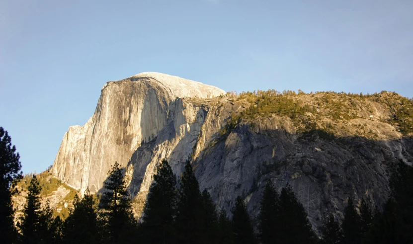 a mountain with trees in the foreground and a blue sky in the background, white marble buildings, yosemite, front lit, dome