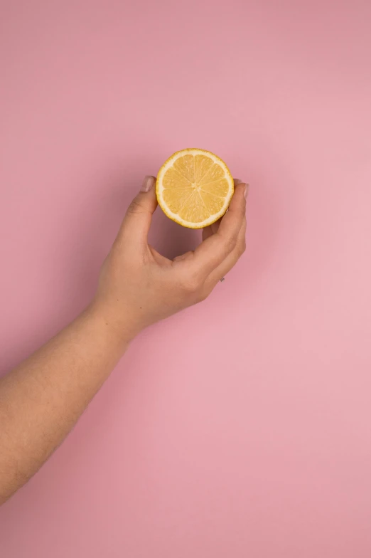 a person holding a half of an orange, aestheticism, pink and yellow, lemonlight, dramatic product shot, lemon