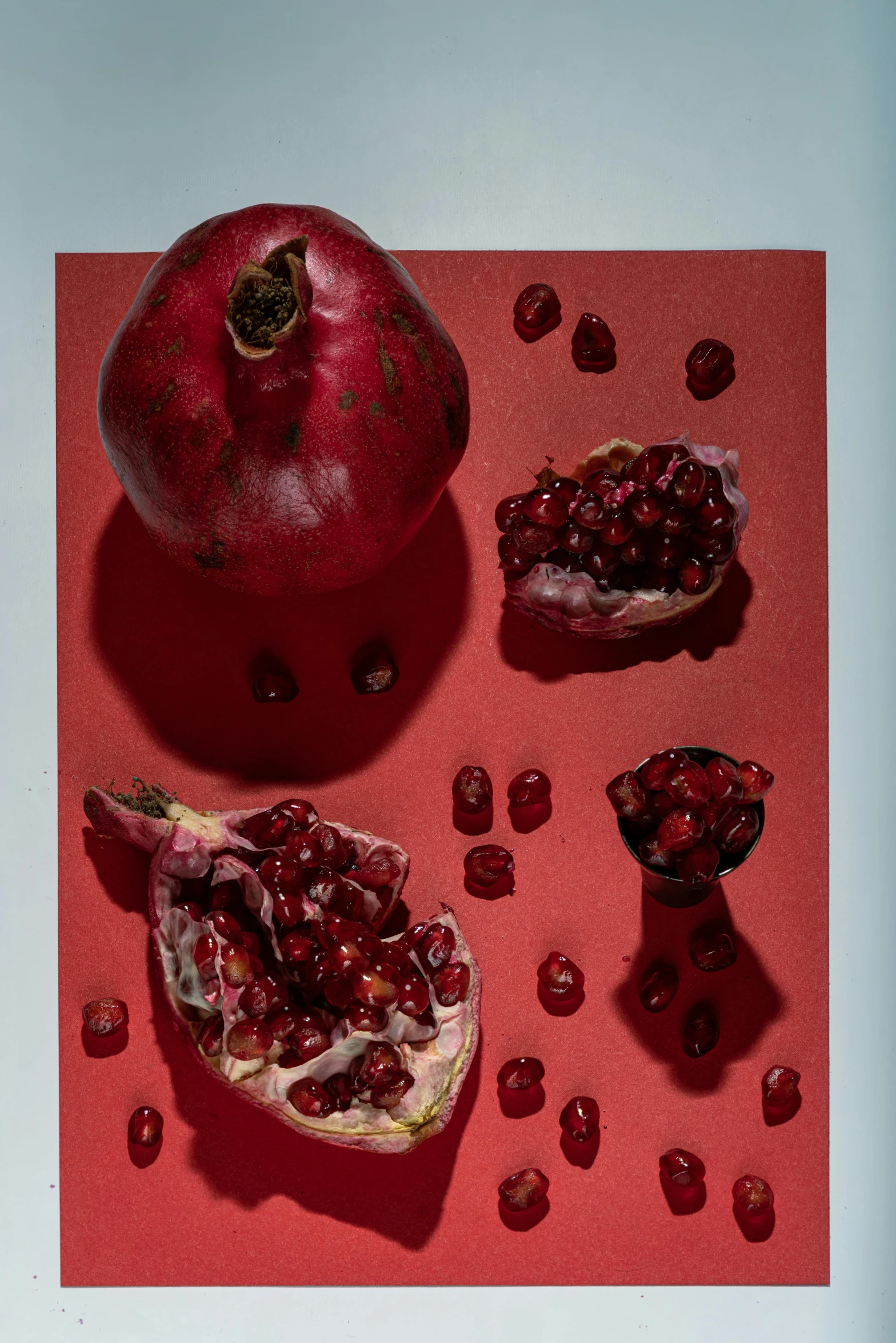 a pomegranate sitting on top of a red surface, plates of fruit, like a catalog photograph, seeds, ignant