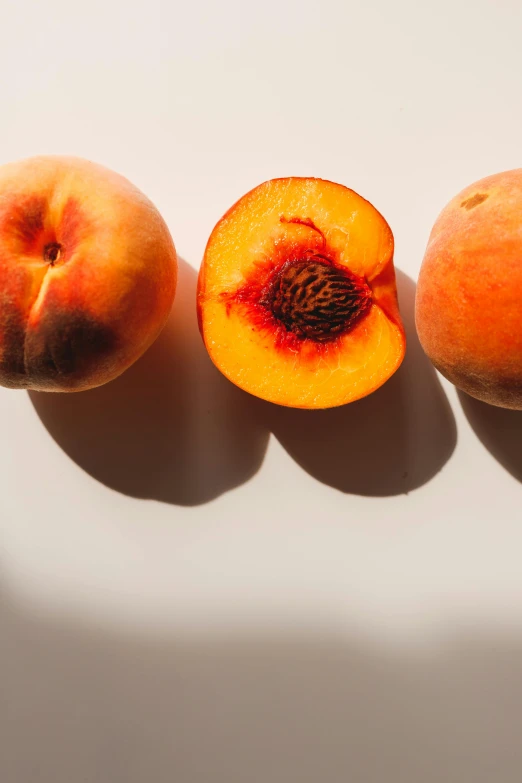 three peaches sitting next to each other on a white surface, inspired by Jacopo Bellini, trending on unsplash, full sun, uncrop, looking from behind, local foods