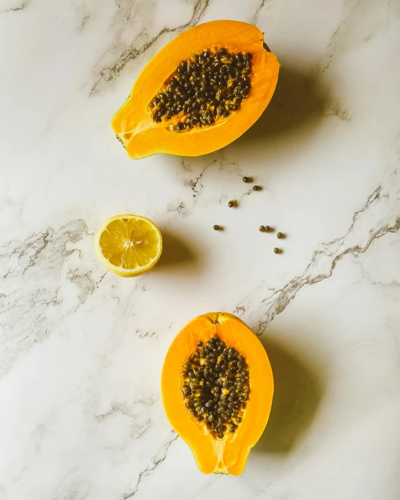 a sliced papana sitting on top of a marble counter, by Carey Morris, trending on unsplash, yellow-orange, seeds, malaysian, 🐿🍸🍋