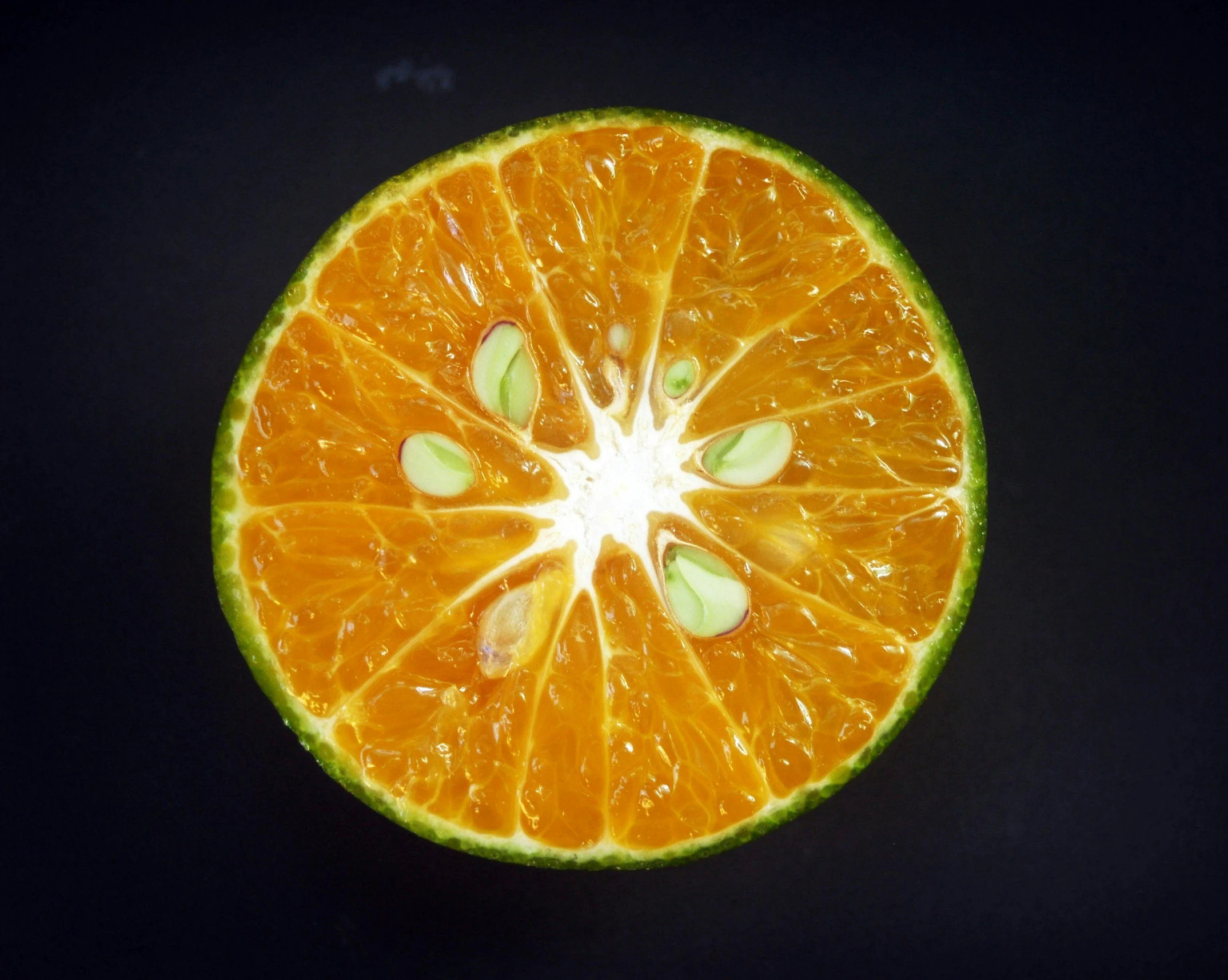 an orange cut in half on a black surface, by Jan Rustem, pexels contest winner, bright green dark orange, highly detailed symmetry, 🍸🍋, star inside