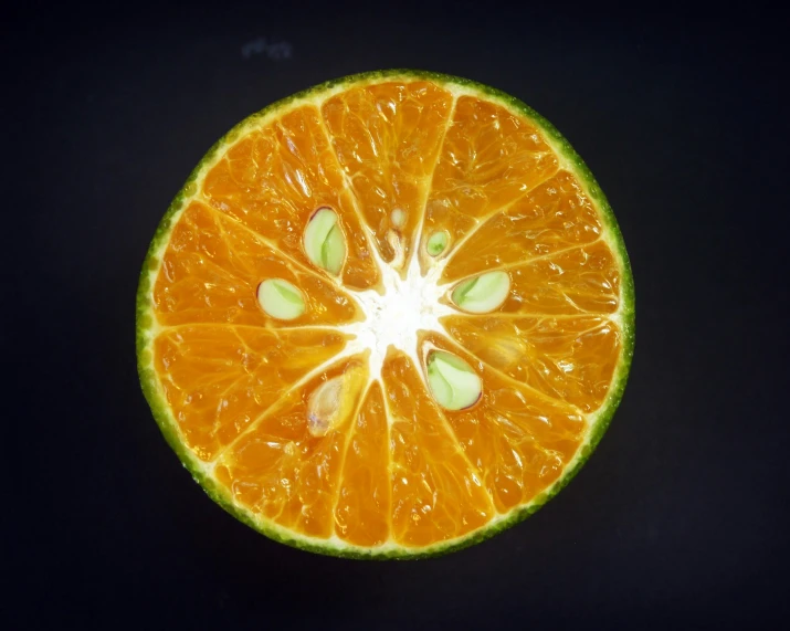 an orange cut in half on a black surface, by Jan Rustem, pexels contest winner, bright green dark orange, highly detailed symmetry, 🍸🍋, star inside