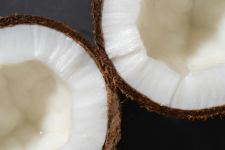 two halves of a coconut sitting on top of a table, by Carey Morris, trending on unsplash, hurufiyya, on black background, background image, close-up product photo, full frame image