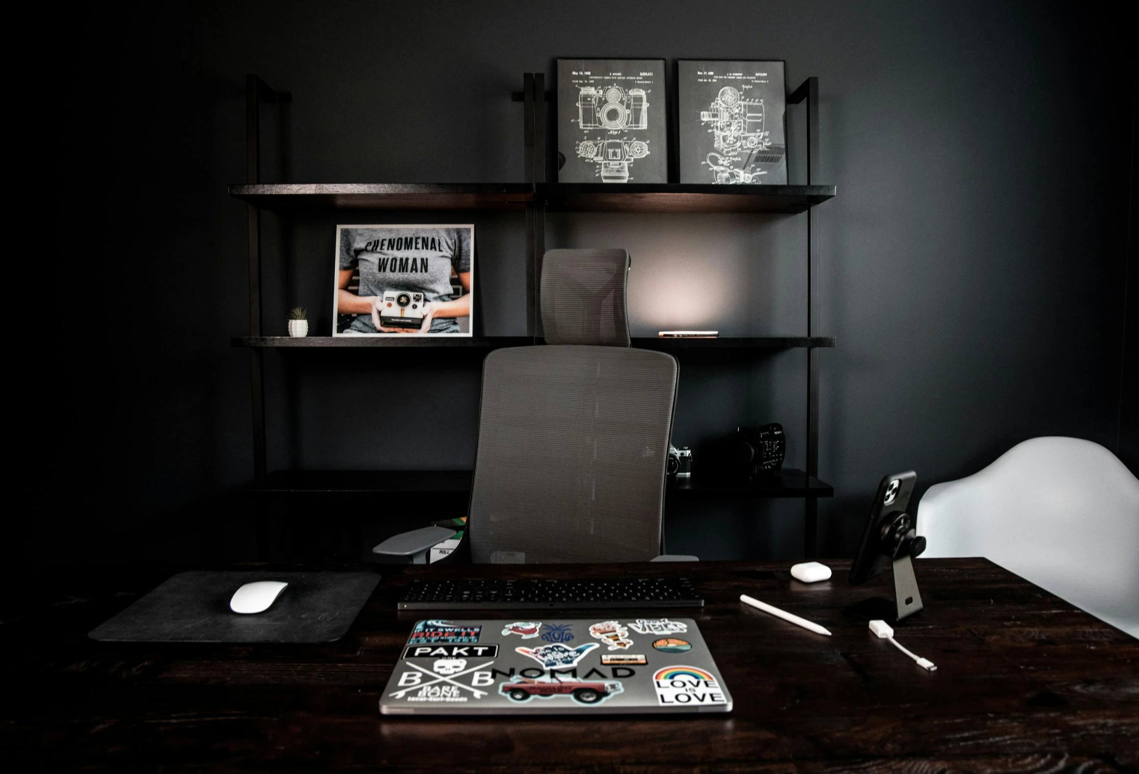 a laptop computer sitting on top of a wooden desk, grey and dark theme, stickers, gaming room, black jewellery