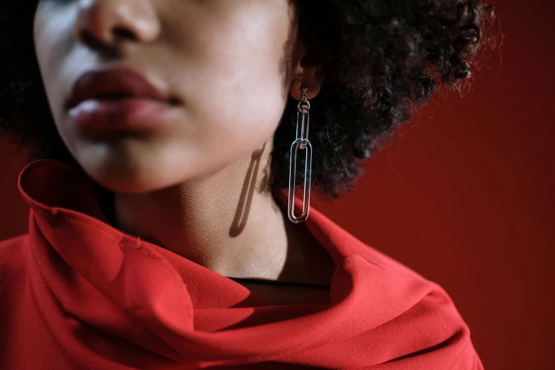 a close up of a person wearing a red shirt, by Emma Andijewska, trending on pexels, bauhaus, long earrings, nubian, made of paperclips, woman holding another woman