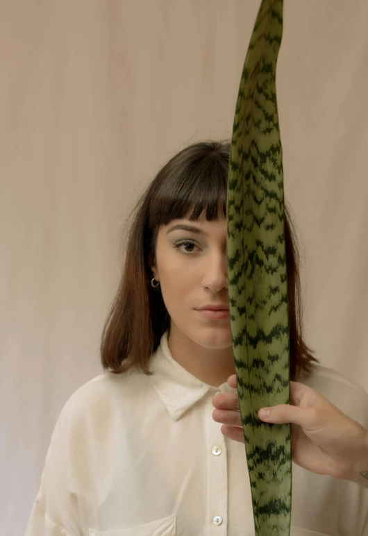 a woman holding a plant in front of her face, an album cover, by Ellen Gallagher, ana de armas portrait, holding a thick staff, close - up studio photo, patterned