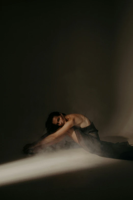 a woman sitting on a bed in a dark room, inspired by Elsa Bleda, modern dance aesthetic, sun behind him, crawling on the ground, promo image